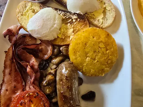 A big breakfast: bacon, sausage, mushrooms, tomato, a hash brown and poached eggs on toast