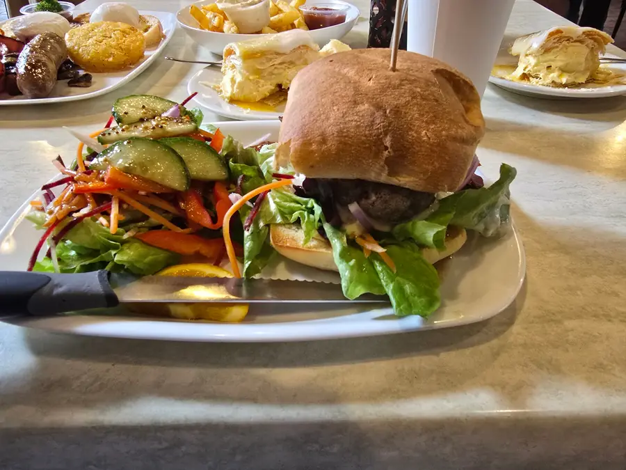 A burger on a toasted bun with a colourful side salad