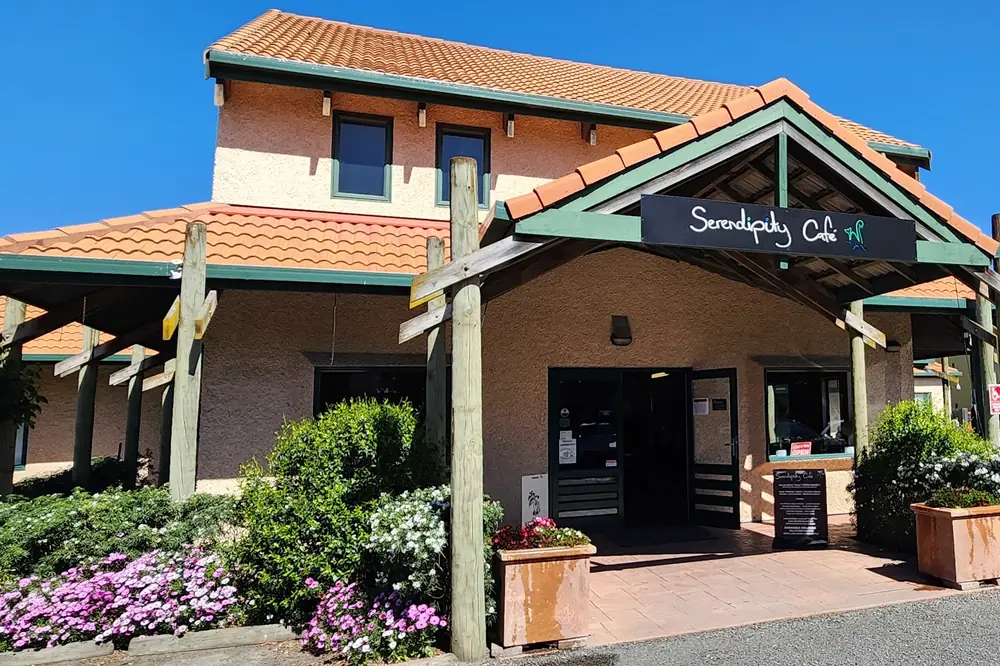The café from the car park: terracotta roof, green trim and the hand-lettered Serendipity Café sign over the door