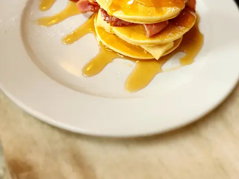 Pancakes stacked with bacon and syrup